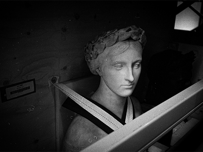 a black and white image of a statue in a corridor 