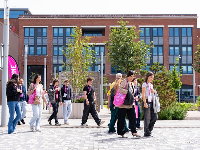 Prospective students exploring a university campus during an open day, walking through a landscaped courtyard in front of a modern campus building.