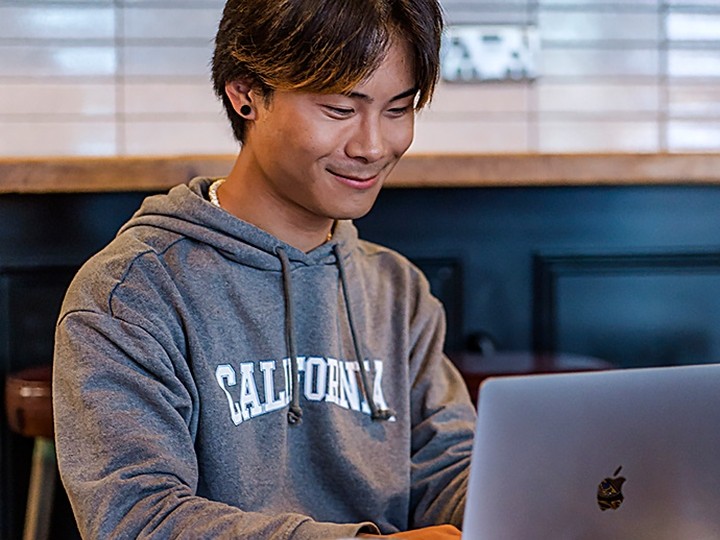 A young man using a laptop in a café.  