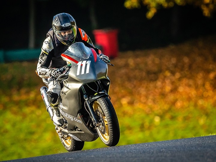 Ilias crouched over the handlebars of a motorbike on a tarmac track.
