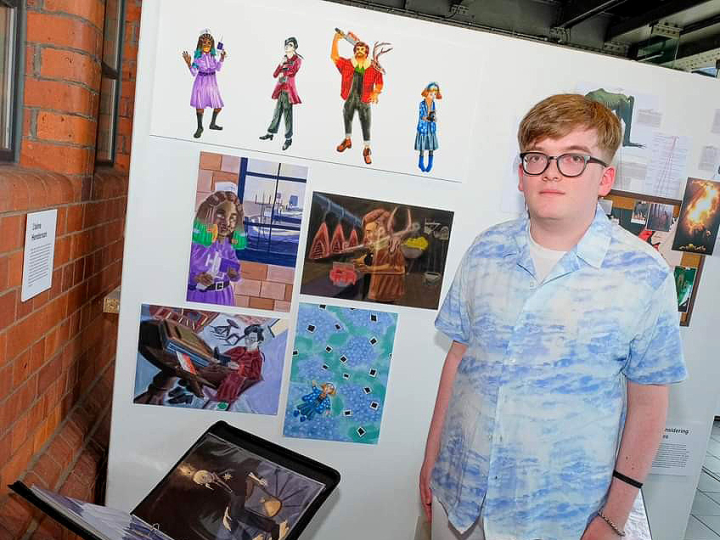 Blaine Henderson stands next to a display of his illustrations. 