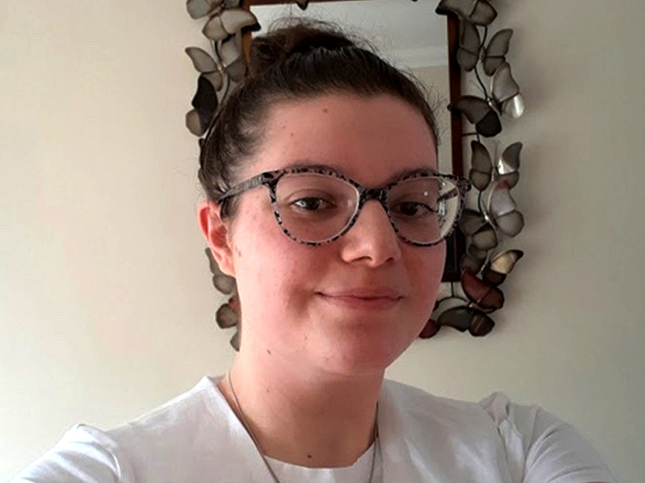 Sophie Larcombe smiles for a selfie in front of a mirror edged with metal butterflies.