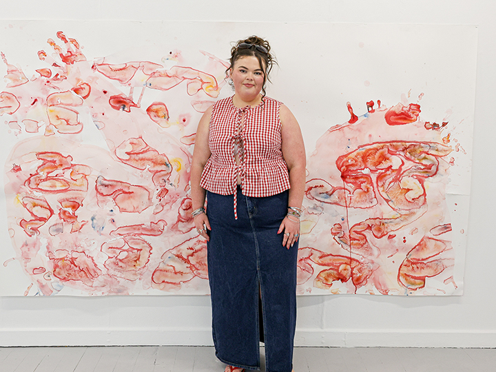 student in front of art work smiling