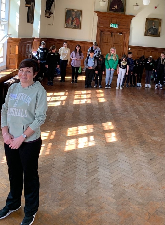 Grŵp o blant blwyddyn chwech o ysgol gynradd mewn neuadd yn cymryd rhan mewn gweithdy drama sy’n cael ei redeg gan fyfyrwyr blwyddyn 2 y cwrs Celfyddydau Perfformio.