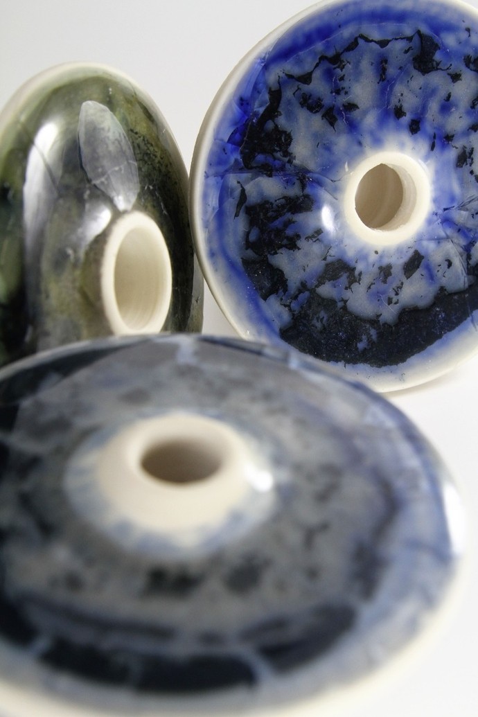 Close up of three ceramic rings designed by Zach Dunlap; two are white and blue, one is green.