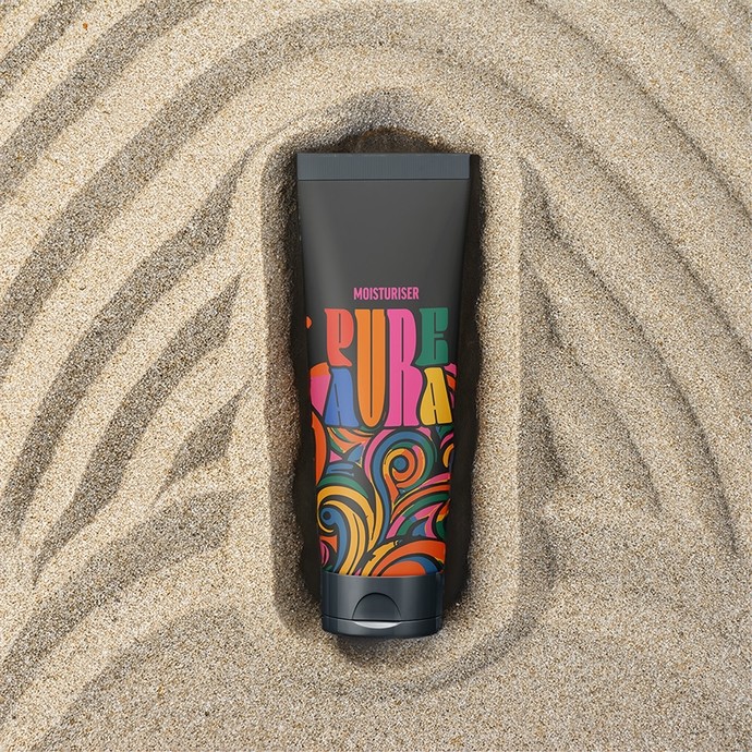 A tube of moisturiser lying in sand shaped into a pattern of repeating arches; the tube is black with colourful swirling designs; the brand name pure aura has been written with six letters; a single 'u' and 'r' extend vertically to take up space in both words. 