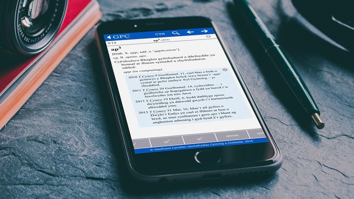 A phone displaying the Geriadur Prifsygol Cymru app, open on the Welsh definition of app.
