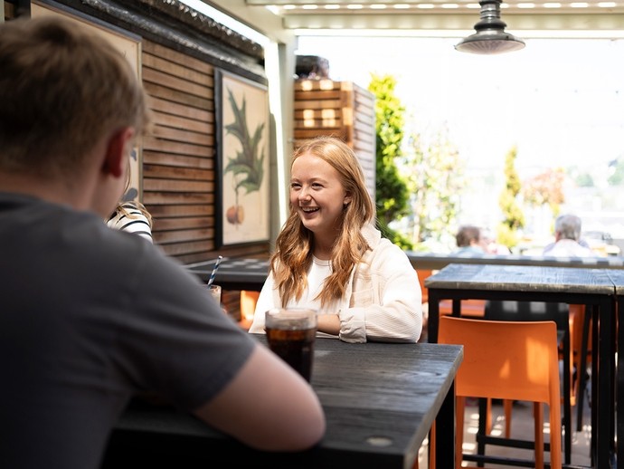 A young woman laughs in a sunny open-air bar.
