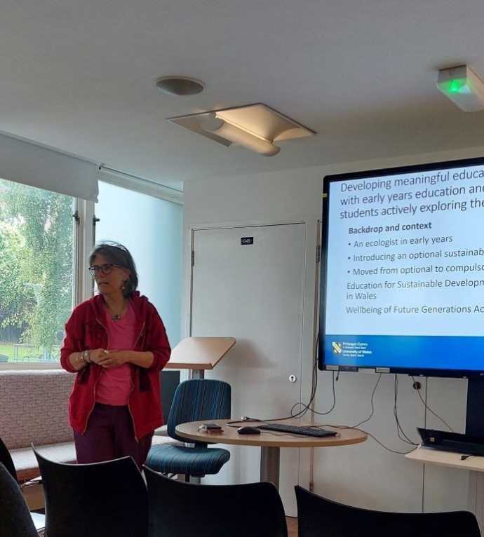 an image of Glenda presenting her research in front of a presentation screen
