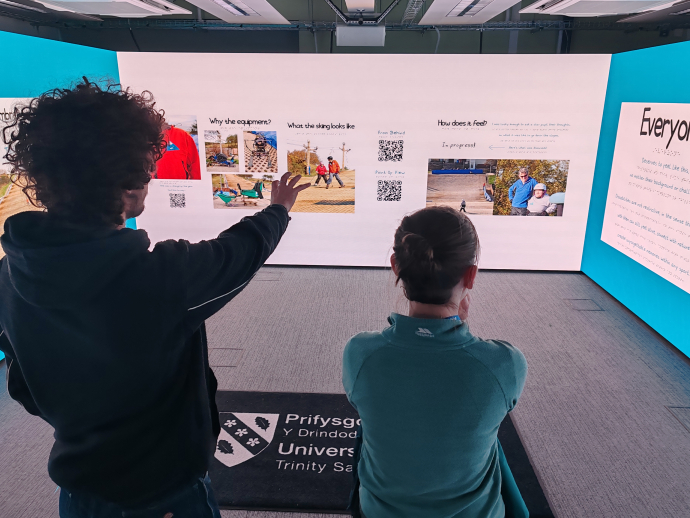 a student showcasing his accessibility in adventure presentation to stakeholders in the immersive rooms