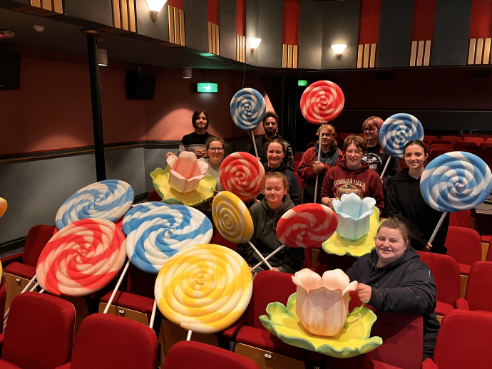 BA Set Design students sitting down in the Lyric theatre holding the giant lollies that they've created for the production 