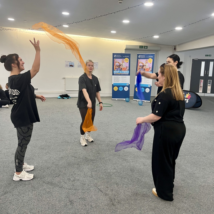 a group of teachers on a training course throwing scarves at each other 