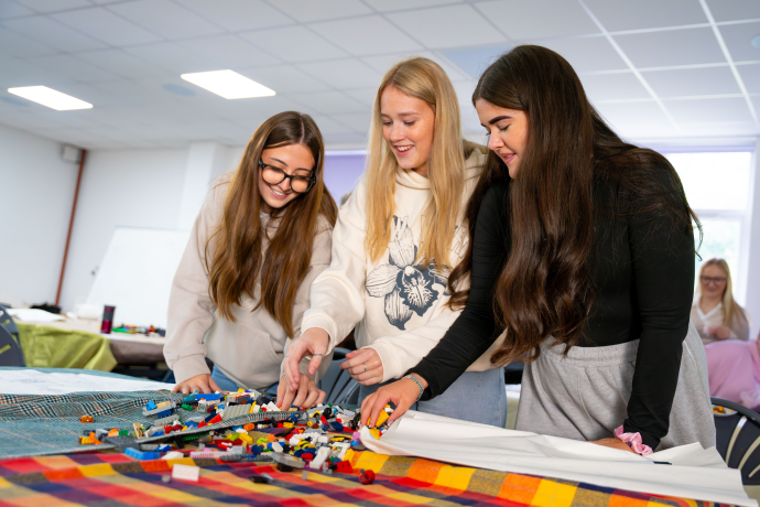 three girls standing in front of lego