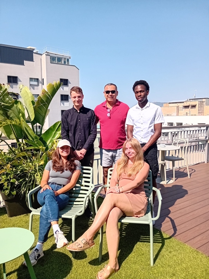 a group of students and lecturers sitting and standing outside 