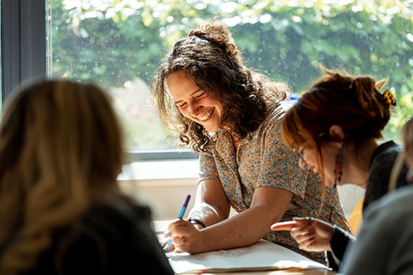 Student holding pen and smiling