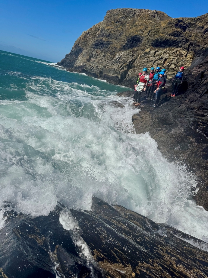 Students coasteering standing on the edge ready to jump into the sea