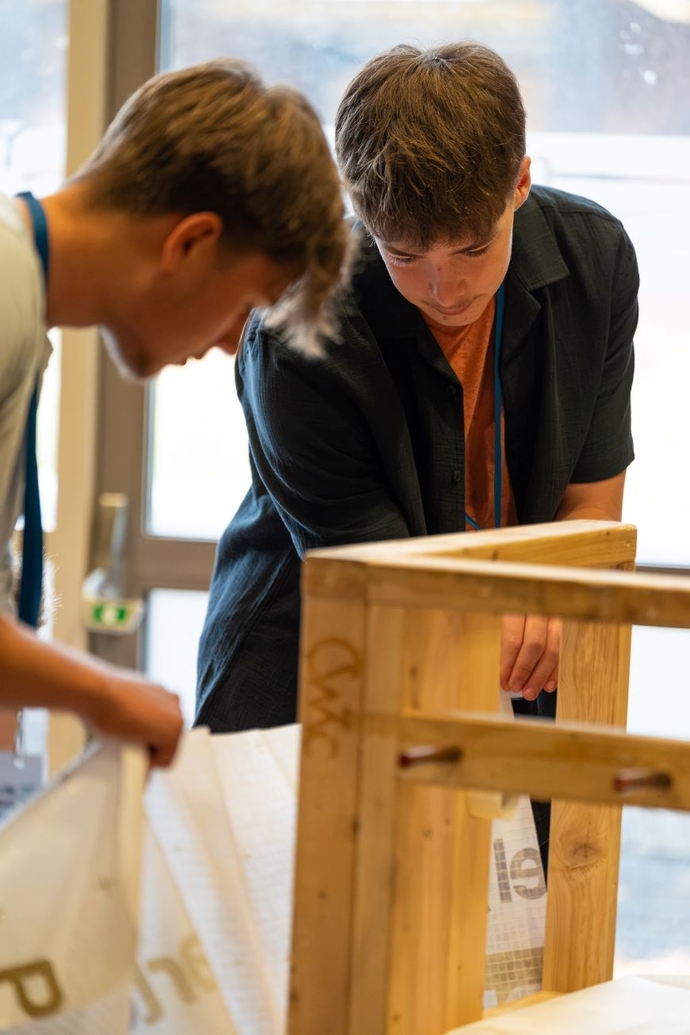 Two students working on a wooden structure.
