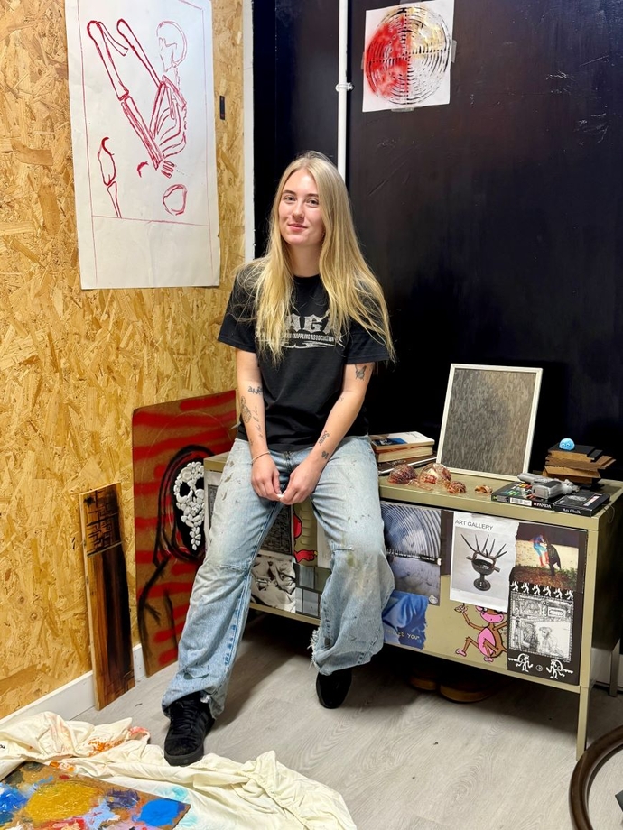 A student in a workshop surrounded by her creative work.
