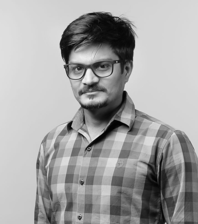 A mono portrait image of a man wearing glasses and a checked shirt.