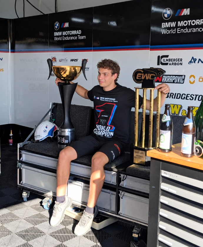 A man sitting in a workshop holding a trophy.