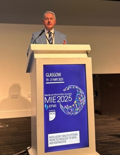Dr Philip Scott talking in front of a blue podium