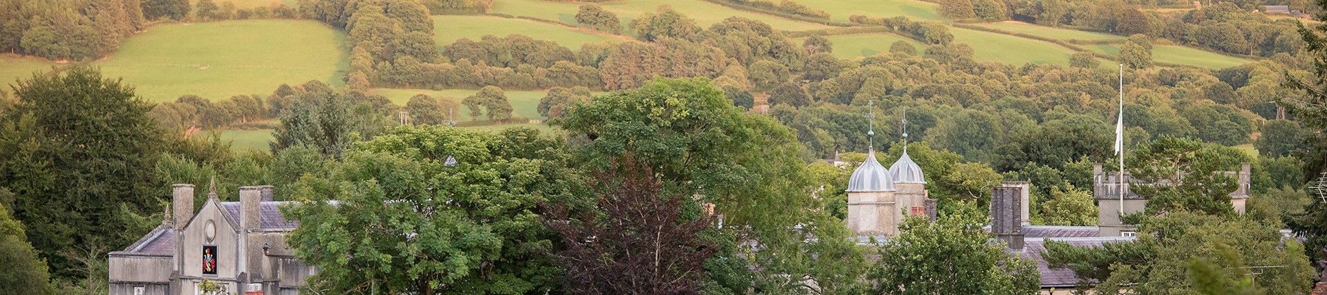 Roof of the college in Lampeter with green fields and trees.