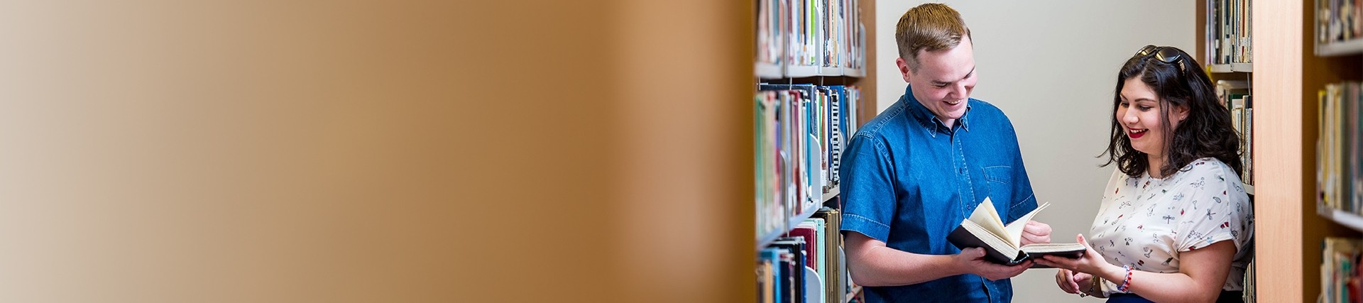 Two students looking at a book in a library