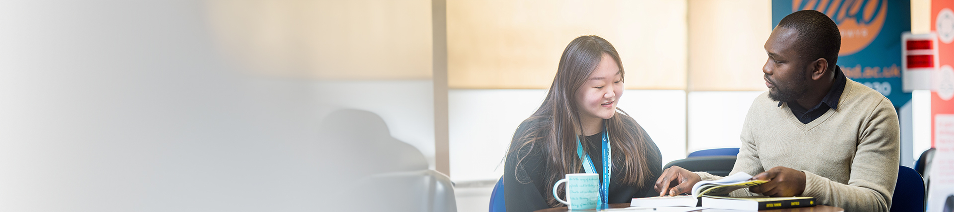 A member of staff and a student discussing work at a table