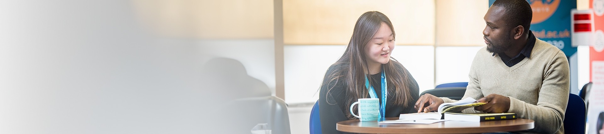 A member of staff and a student discussing work at a table