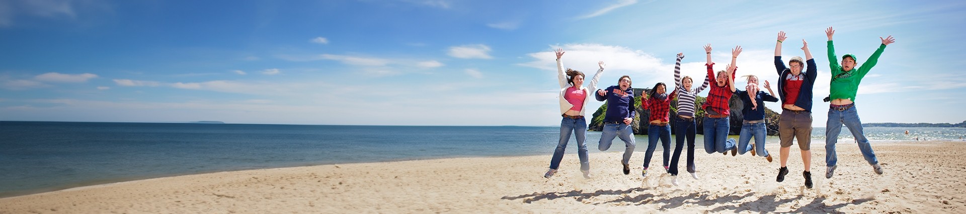 Group of students jumping at the beach