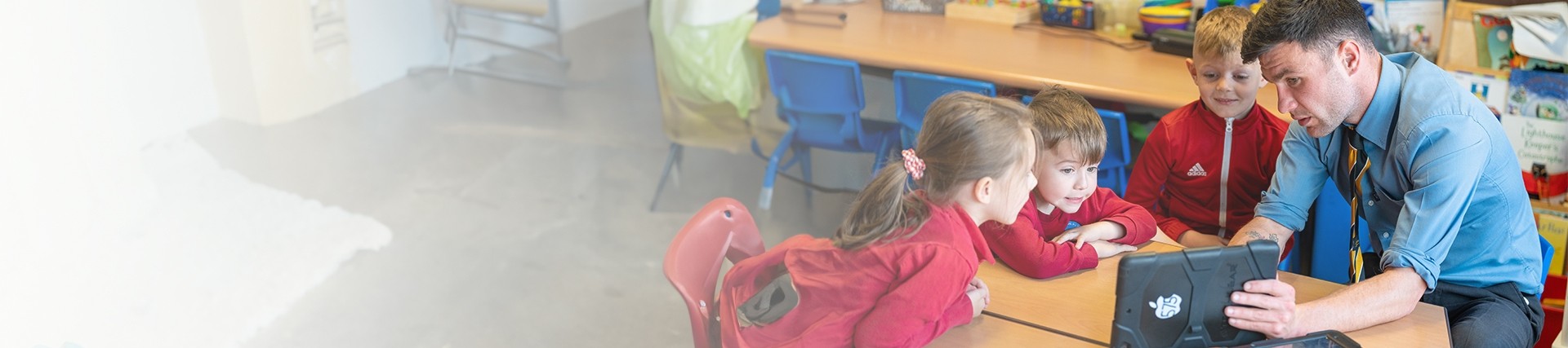 Teacher showing three primary students an educational video