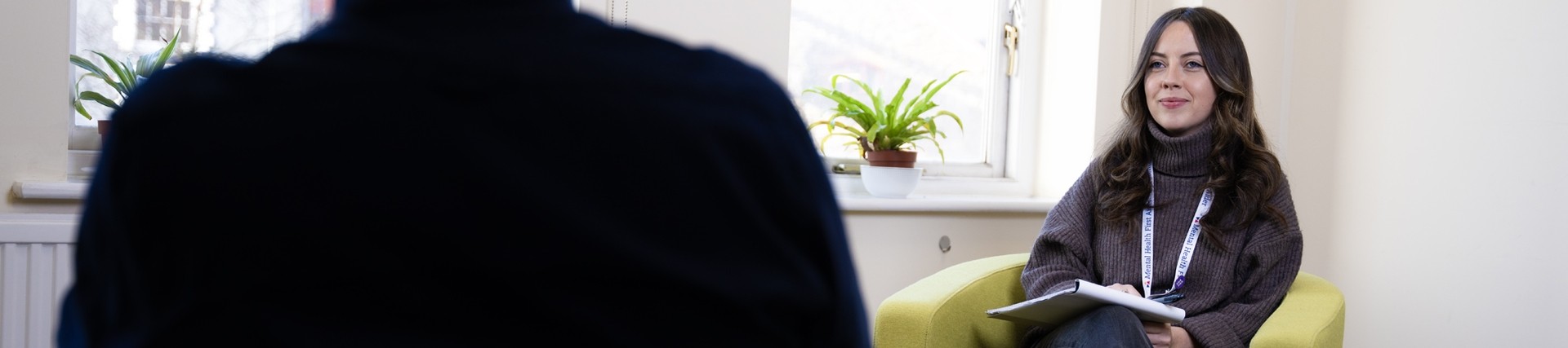 Support officer sitting on a green chair and holding a notepad