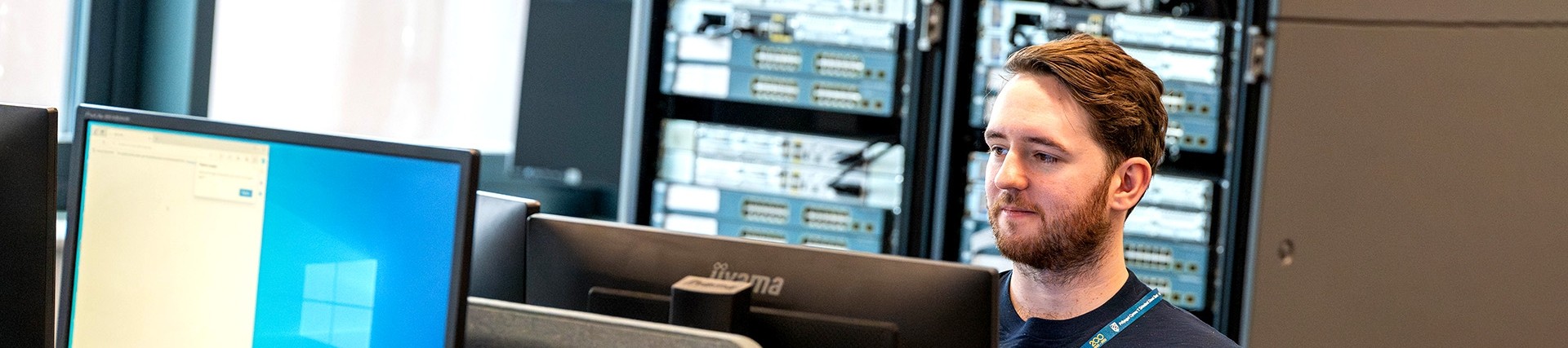 A student sits at a computer; a server is visible behind him.