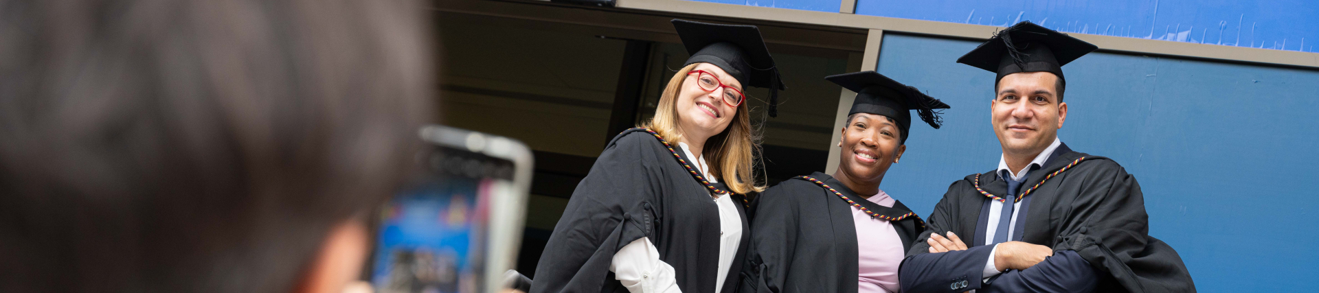 a person taking a photo of three graduates