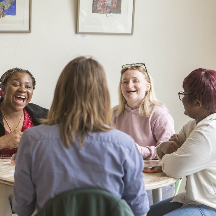 Four students sitting at a coffee table laughing together