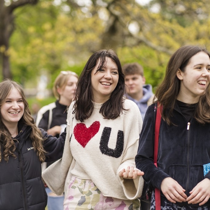 Three students walking together in the park laughing