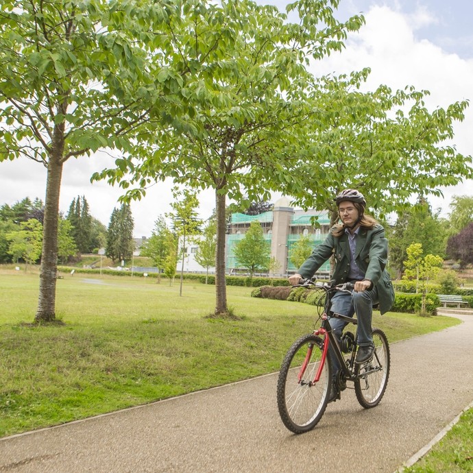 student cycling through woods on path at Lampeter campus