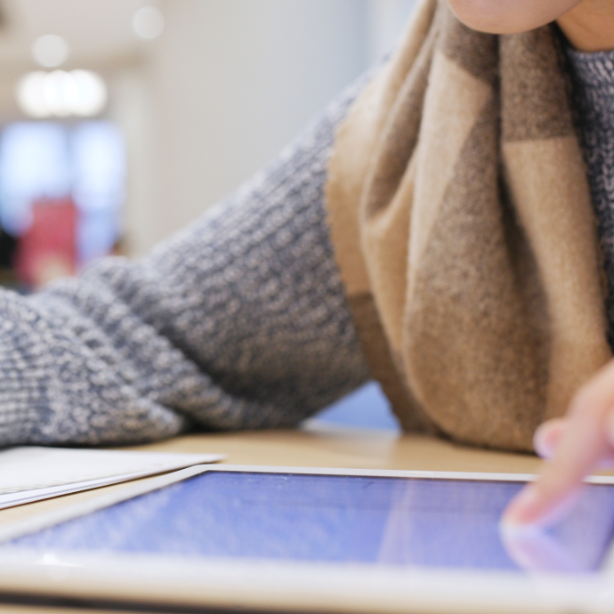 Student working on a tablet and writing on a notepad