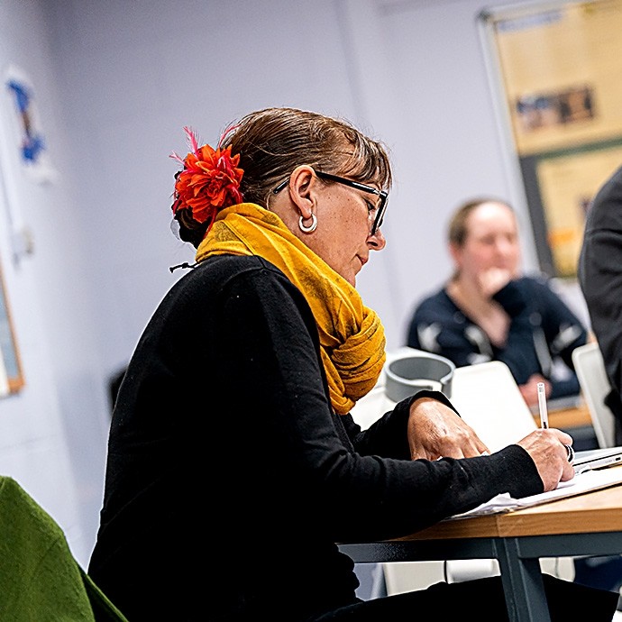 A woman making notes in class.