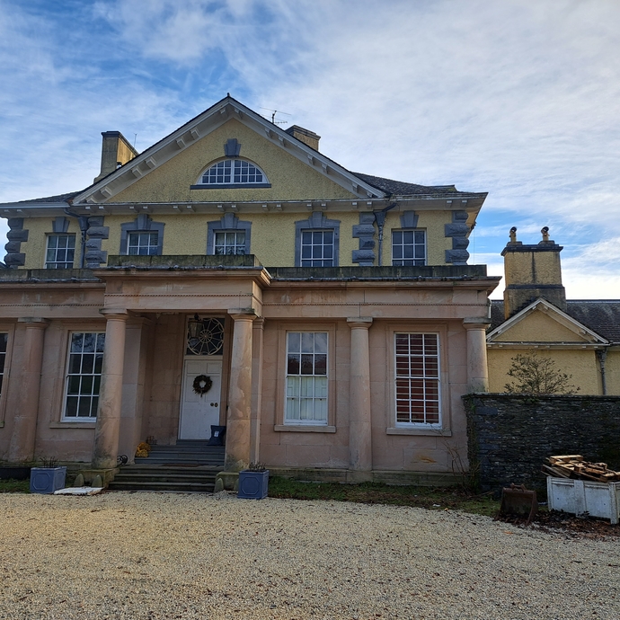 A stone fronted building with a wide sweeping gravel driveway in front.