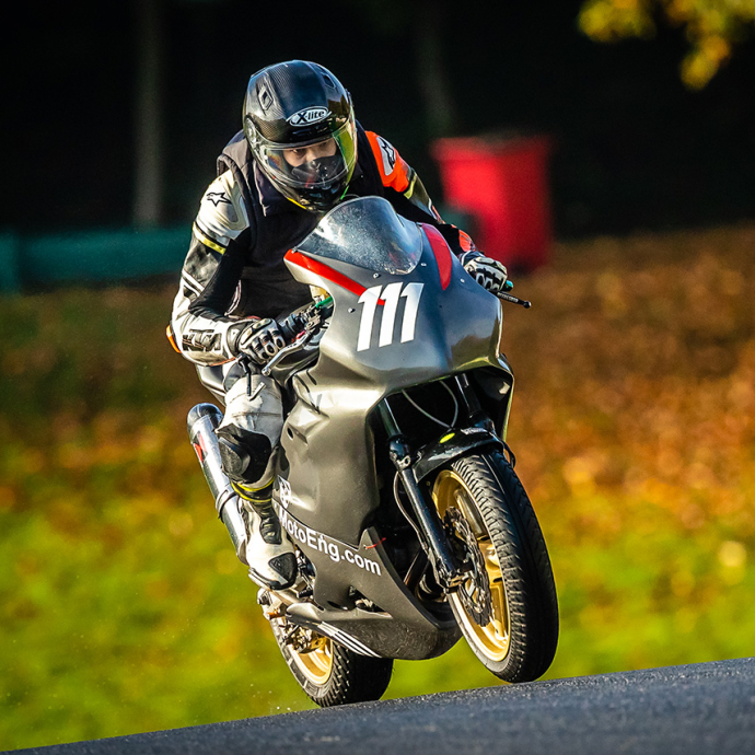 Ilias crouched over the handlebars of a motorbike on a tarmac track. 