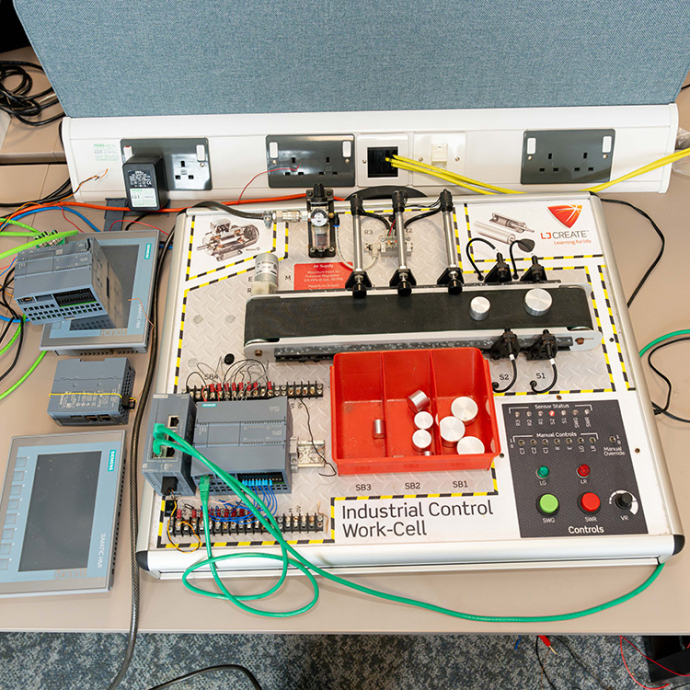 An industrial control work-cell: a complex board including control switches, pneumatic cyclinders, and LED lights.