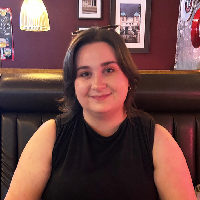 Rebecca Hodgson sits in a booth in a bar and smiles towards the camera.