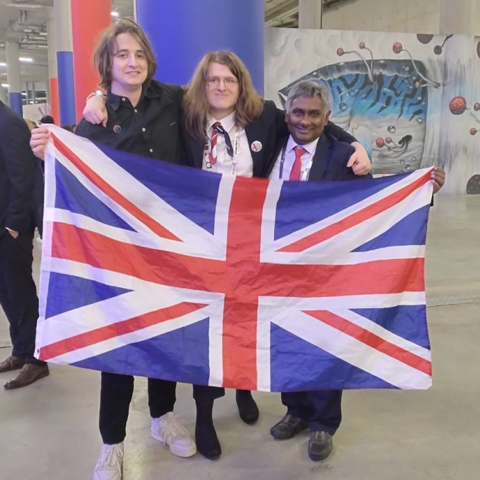 Three people celebrating holding a red, white and blue flag.