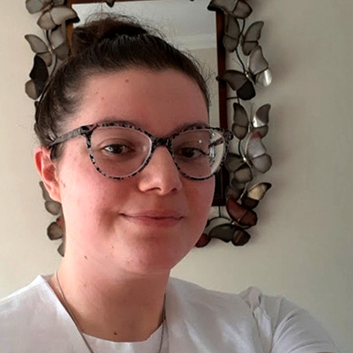 Sophie Larcombe smiles for a selfie in front of a mirror edged with metal butterflies.