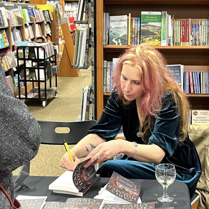 Image of Carly Holmes signing one of her books