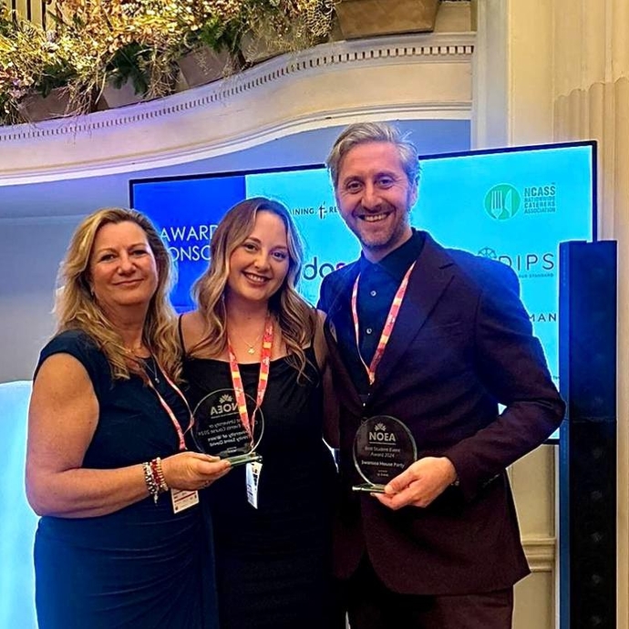 A group of three happy, smiling people clutching awards at a presentation evening.