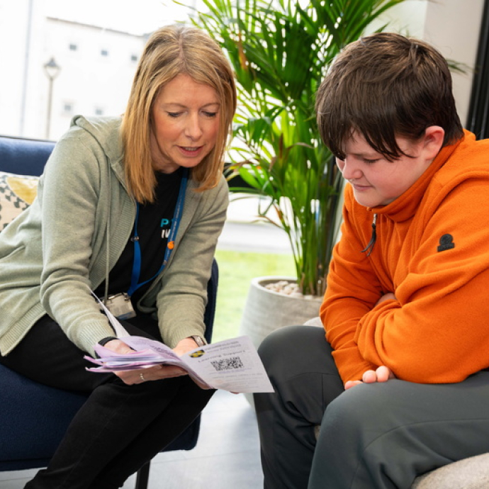 Staff member handing a brochure to a student