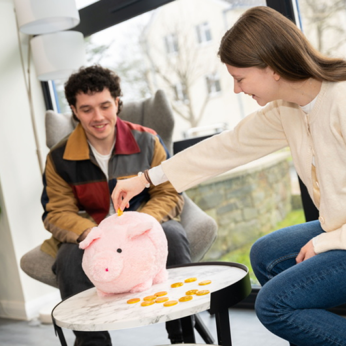 Two students putting money into piggy bank