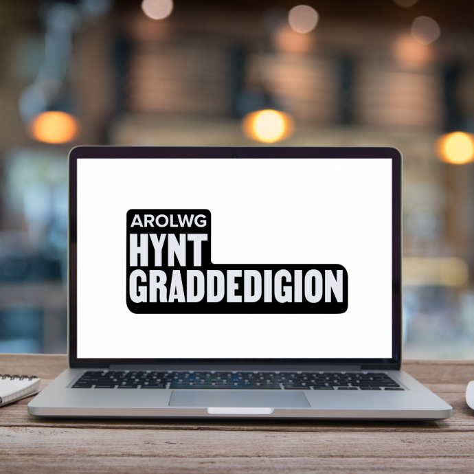 gliniadur ar fwrdd gyda 'Arolwg Hynt Graddedigion' ar y sgrin